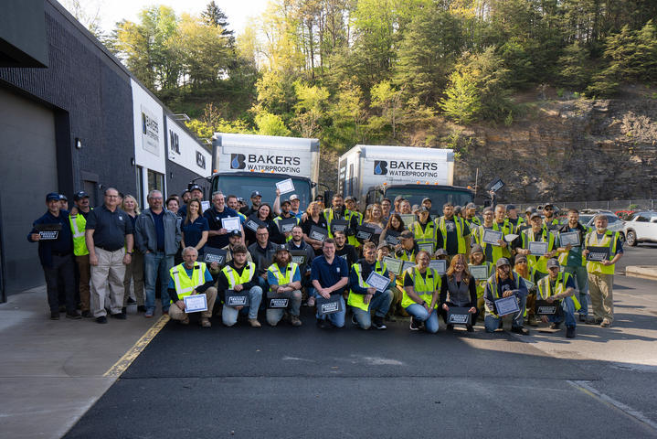 Baker's employee standing in front of Baker's waterproofing box trucks.