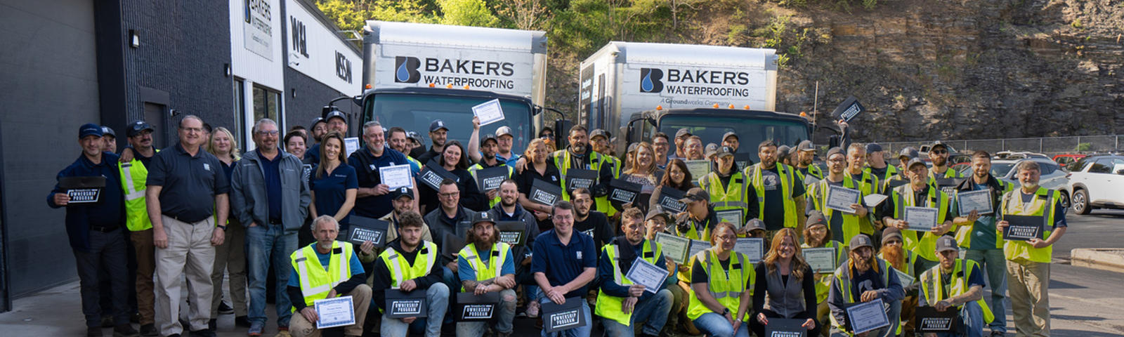 Baker's employee standing in front of Baker's waterproofing box trucks.