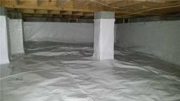A clean, sealed crawl space with a white vapor barrier covering the floor, walls, and support pillars.