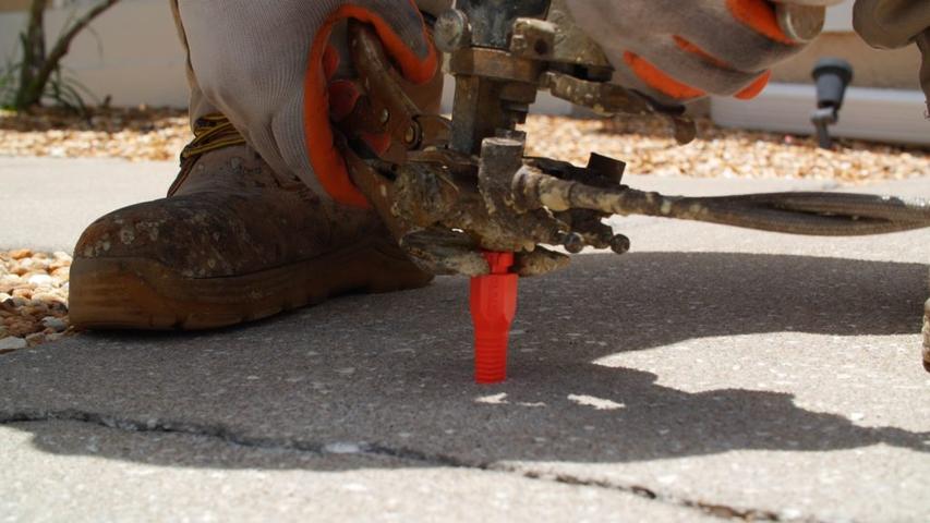 AFS crew member conducting a PolyRenewal injection into concrete slab.