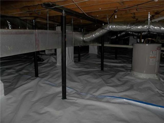 Crawl space with moisture barrier, metal supports, pipes, and an insulated floor.
