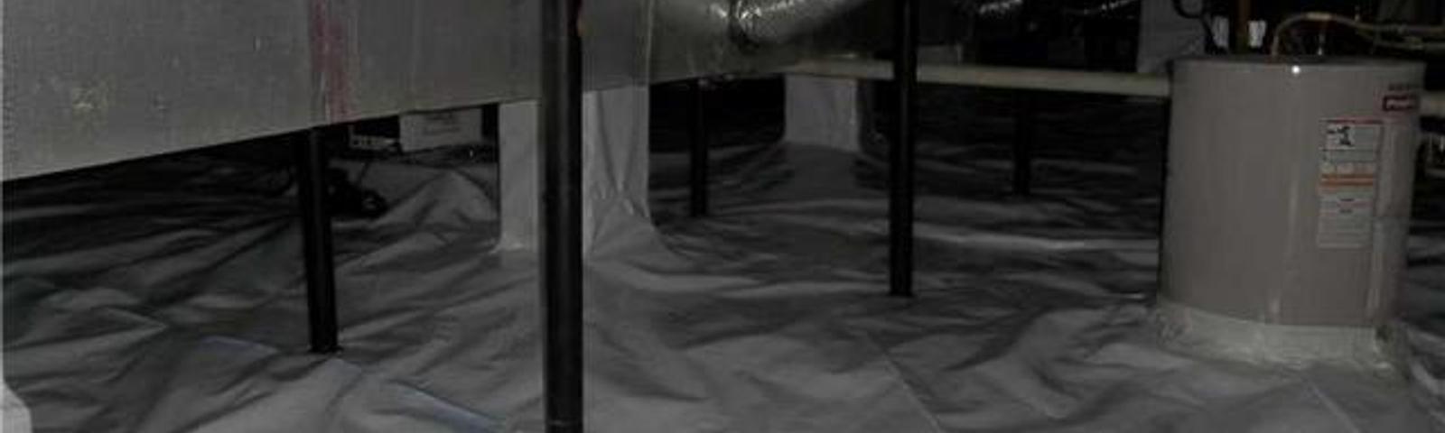 Crawl space with moisture barrier, metal supports, pipes, and an insulated floor.