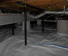 Crawl space with moisture barrier, metal supports, pipes, and an insulated floor.