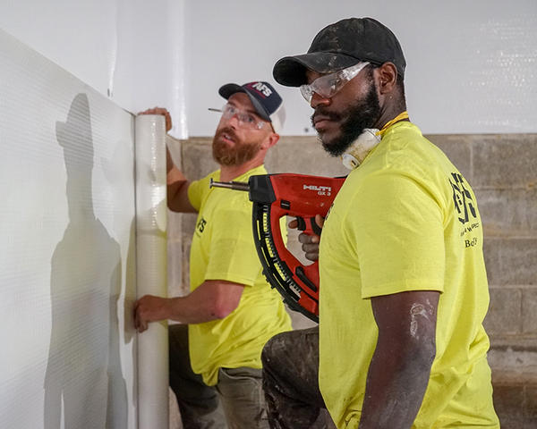 workers installing vapor barrier in basement