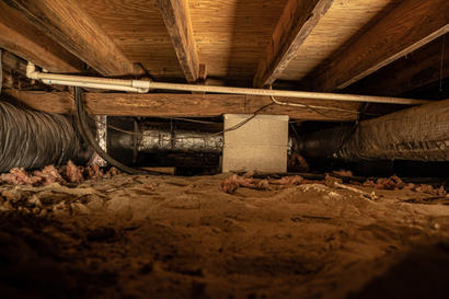 Dirt crawl space with fallen insulation.