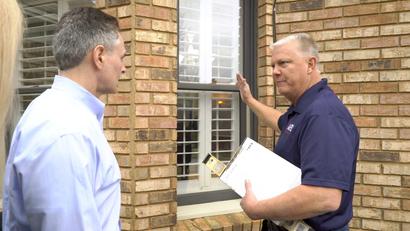 AFS Inspector speaking with homeowner while pointing at home.
