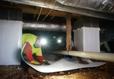 Worker waterproofing crawlspace with vapor barrier