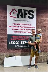 AFS staff holds his son in front of AFS poster