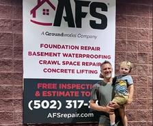 AFS staff holds his son in front of AFS poster
