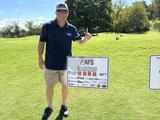 AFS teammate standing by a company sponsorship sign at the Ronald McDonald House Charities of Knoxville’s 2024 Golf Tournament