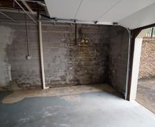 Concrete block garage wall with water stains and peeling paint, next to an open garage door.