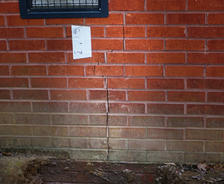 A vertical crack in a red brick wall under a window may signal the need for foundation repair in Birmingham AL.