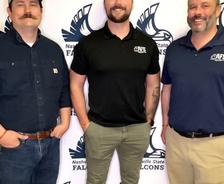 Three men standing in front of a Nashville State Falcons backdrop, smiling and wearing casual shirts.