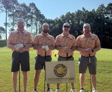 Four AFS crew members holding gold clubs at Aubreighs Army Lemon Face Classic sponsorship event