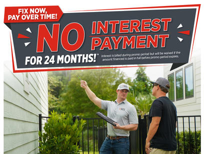 Two men talk outside near houses under a sign advertising no interest payment for 24 months.