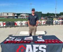an AFS Huntsville employee stands at a company booth during a 2026 Rocket City Trash Pandas game