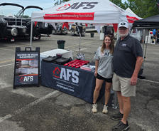 Two people stand by an AFS Sponsors booth with brochures and a banner for foundation and waterproofing services at Logan Martin Lakefest.