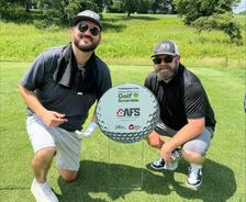 AFS Louisville employees pose next to a sponsorship sign with the AFS logo at the Ronald McDonald House Louisville’s Annual Golf Scramble