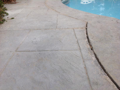 Cracked and unlevel concrete pool deck.