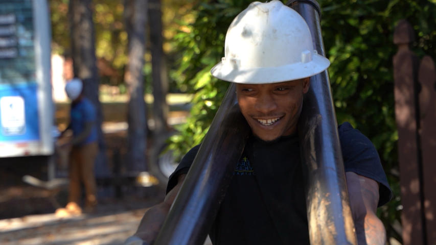 Foundation Systems of Michigan crew member carrying push piers while smiling.