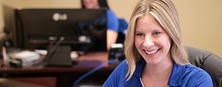 FSM Customer Service Employee smiling while looking at computer.
