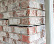 Close-up of a brick wall corner with visible cracks between bricks and signs of structural separation.