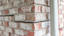 Close-up of a brick wall corner with visible cracks between bricks and signs of structural separation.