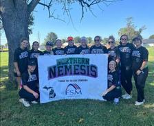 players with the Resto Athletics – YMCA Softball Team, Northern Nemesis, stand next to a banner with their name and the FSM logo