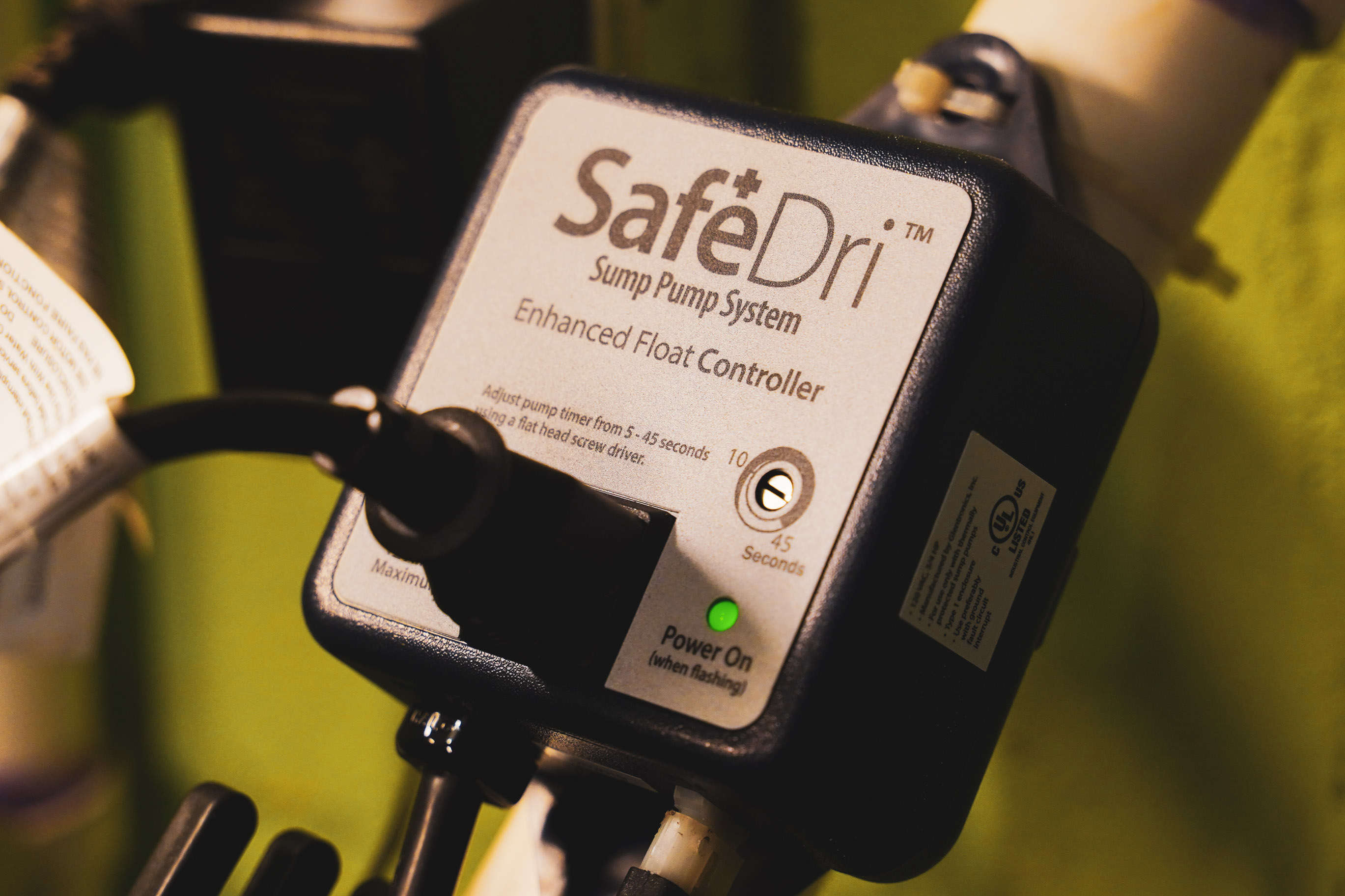 Close-up of a SafeDri sump pump system's enhanced float controller with a glowing green power light, ensuring peace of mind even when the sump pump alarm is going off.