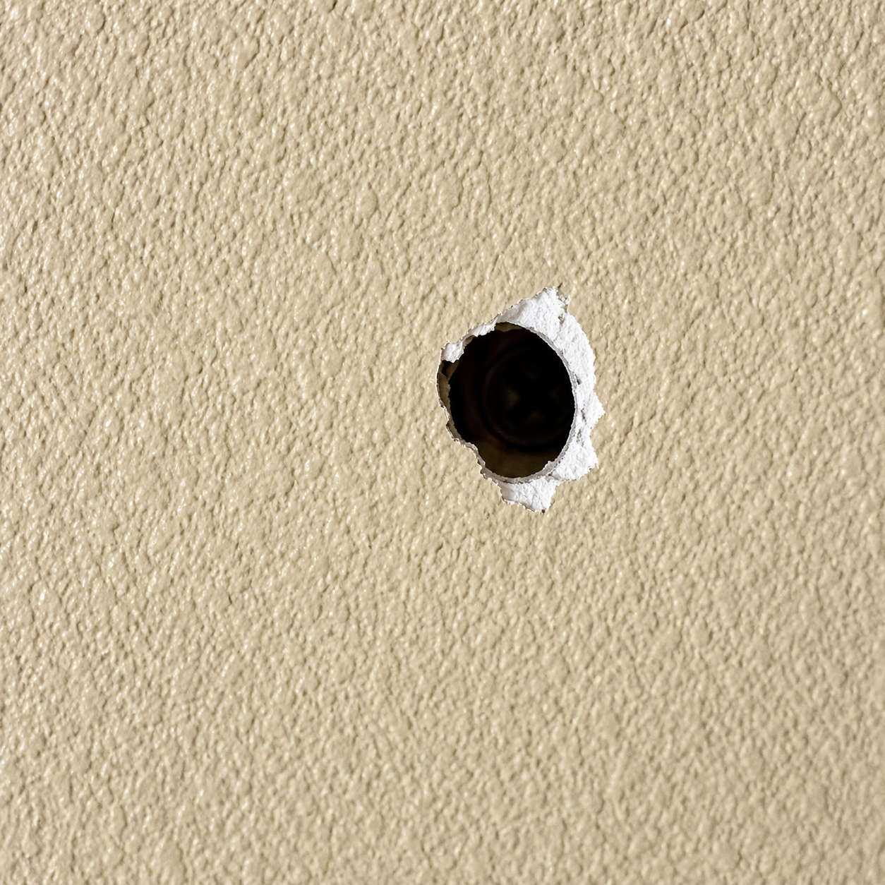 drywall nail pop on beige wall