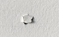Drywall nail pop on interior wall.