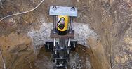 A hydraulic jack, often used alongside push piers, is installed in a dug-out hole for support or lifting.