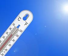A thermometer, like the unpredictable patterns of shrink-swell soil, displays a high temperature under a bright blue sky and radiant sun.