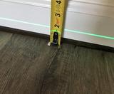 tape measure and laser level indicating uneven floors in house
