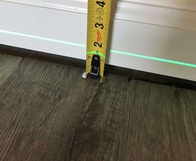 tape measure and laser level indicating uneven floors in house