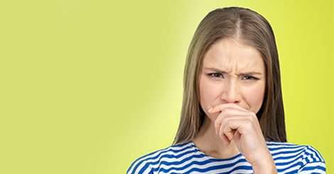 A woman with long hair frowning, wearing a blue and white striped shirt against a light green background, appears as if she’s just stepped out of a musty basement.