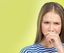 A woman with long hair frowning, wearing a blue and white striped shirt against a light green background, appears as if she’s just stepped out of a musty basement.