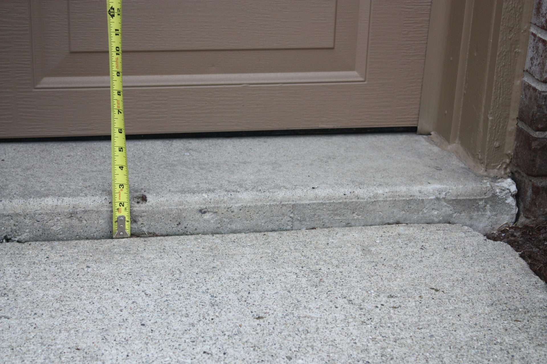 tape measure measuring a sinking concrete slab