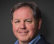 Steve Frey, recently appointed by JES, smiles confidently in a suit against a dark background.