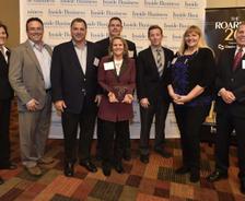 A group of people posing for a photo at a business event with a "Inside Business" banner in the background.