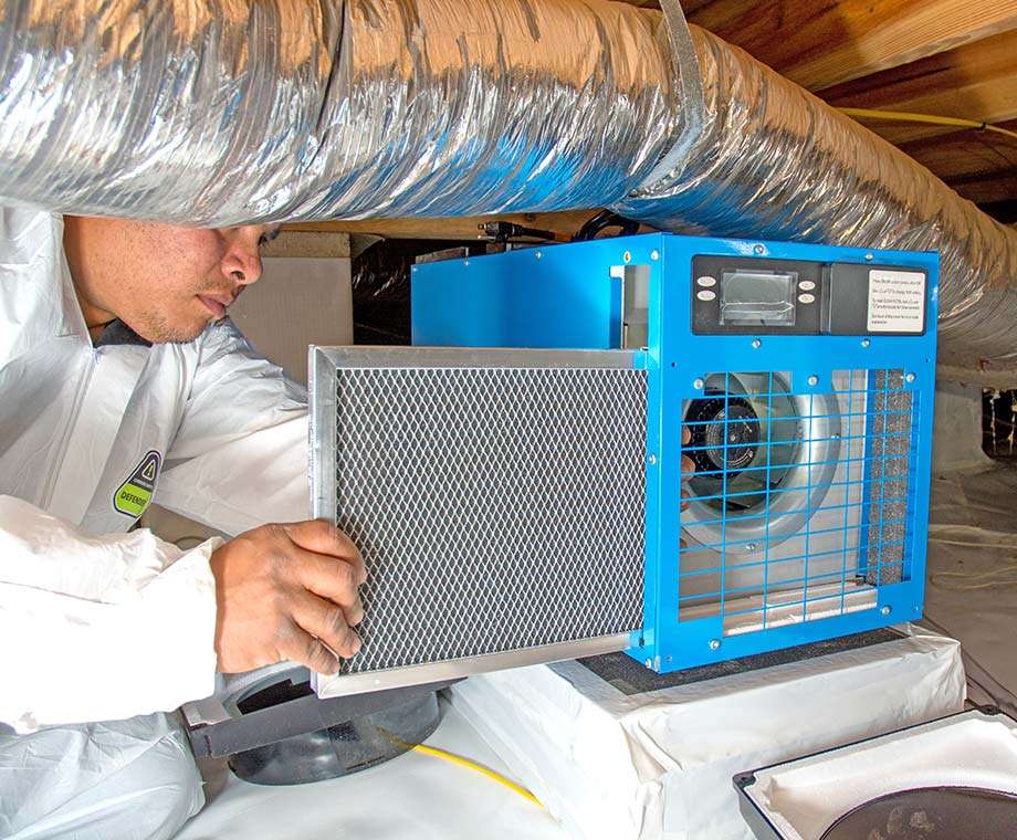 crew member installing a dehumidifier in a crawl space