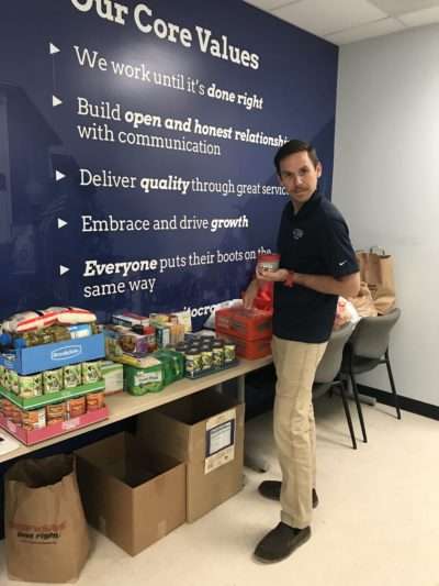 JES employee holding can of nonperishable food.