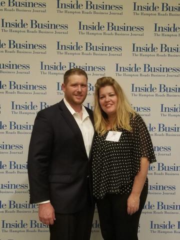 A man in a suit and a woman in a polka dot blouse channel the Roaring 20s as they pose confidently in front of an "Inside Business" backdrop.