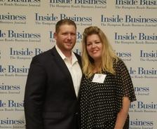A man in a suit and a woman in a polka dot blouse channel the Roaring 20s as they pose confidently in front of an "Inside Business" backdrop.