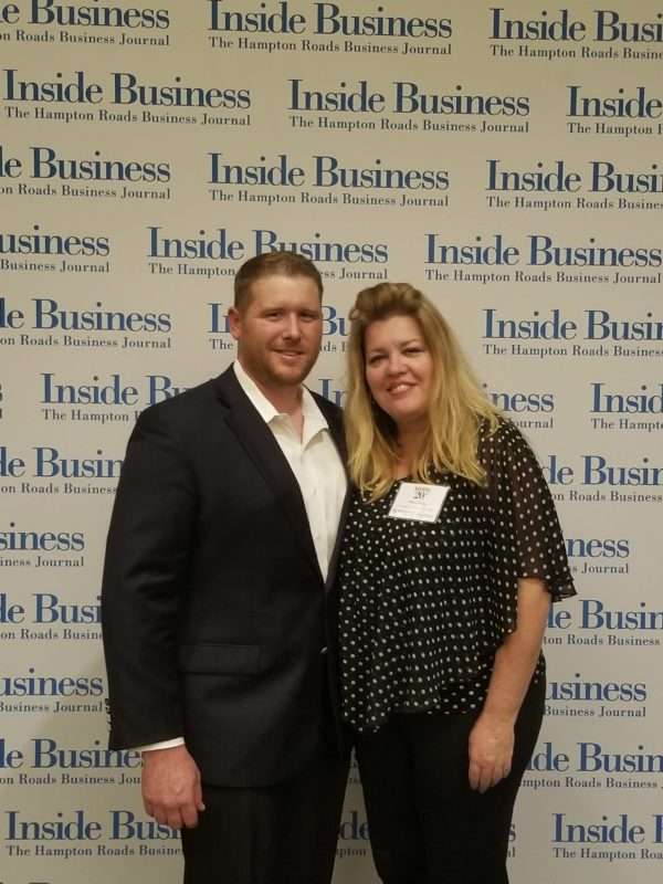 A man in a suit and a woman in a polka dot blouse channel the Roaring 20s as they pose confidently in front of an "Inside Business" backdrop.