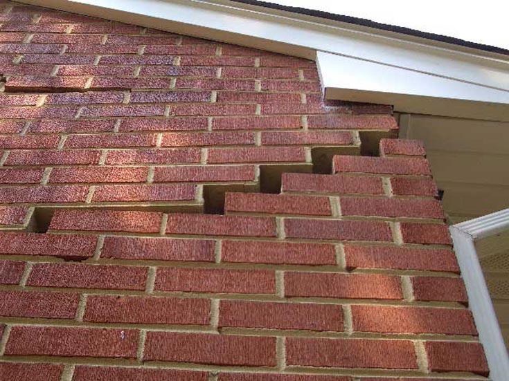 exterior brick wall with cracks and gaps, indicating foundation settlement