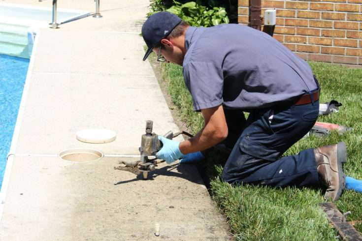 crew member injects polyurethane foam underneath concrete around a swimming pool