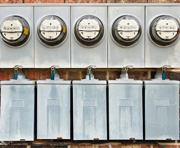 electric meters on the side of a building measuring usage resulting in high electric bills