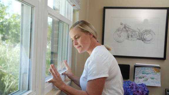 woman opening a window from inside her home