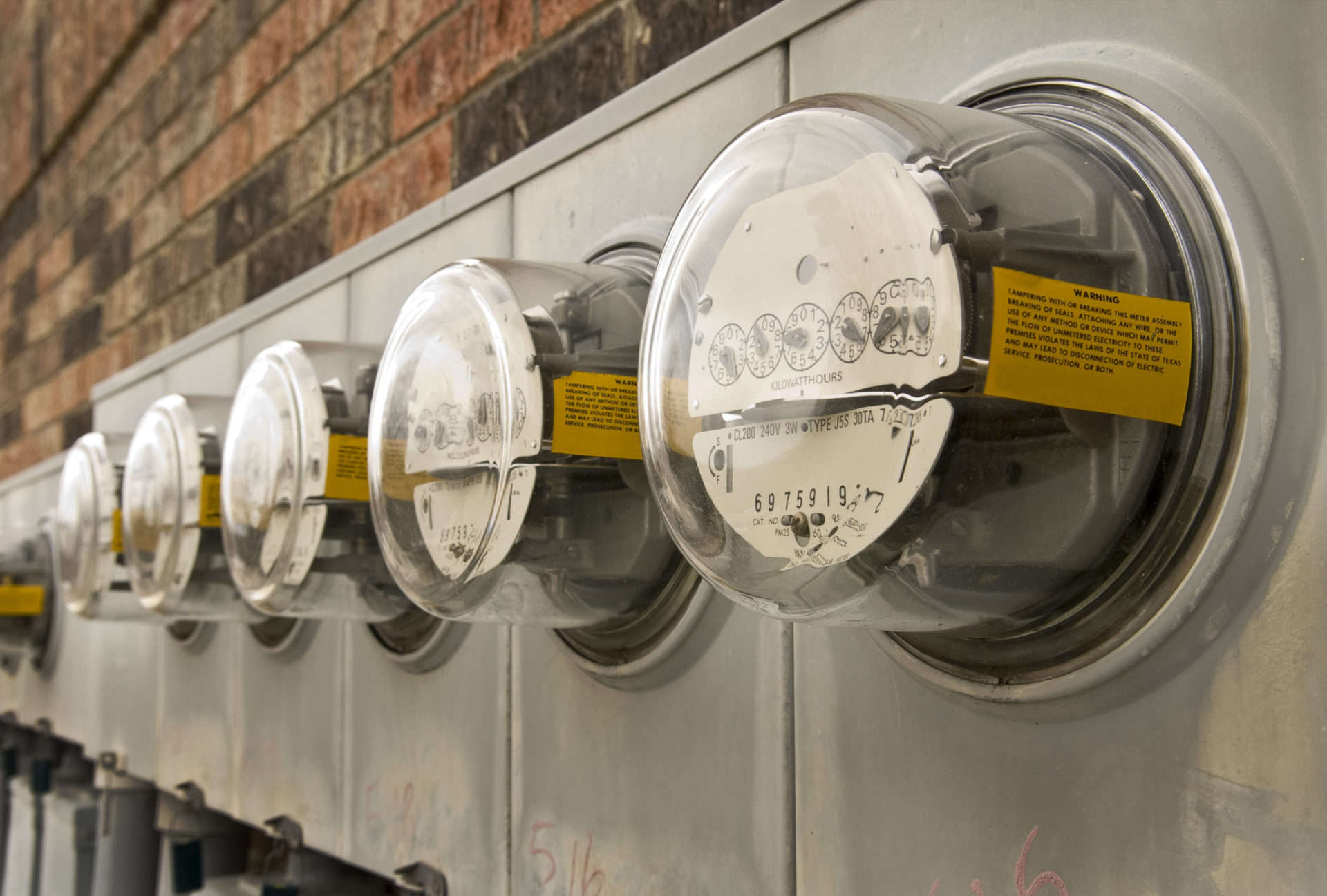 electric meters on the side of a building measuring increased usage resulting in high electric bills